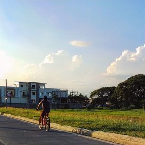 Man riding bicycle on street against sky