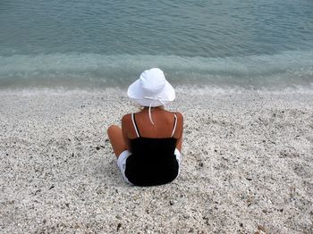 Rear view of woman sitting at sandy beach