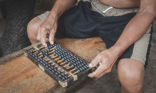 Midsection of man playing with abacus