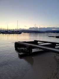 Sailboats moored in marina at sunset