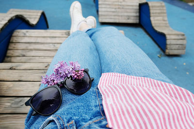 Low section of person wearing sunglasses shoes on wood