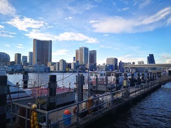 Modern buildings by river against sky in city