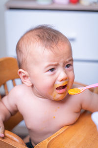 Close-up of cute toddler boy eating food at home