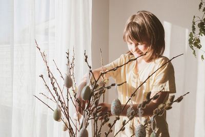 A teenage girl decorates the branches of the house with easter eggs. easter decoration 