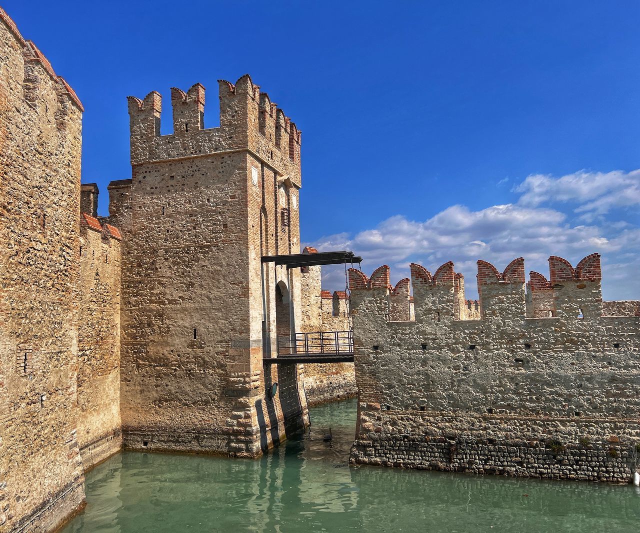 architecture, castle, built structure, water, building exterior, history, moat, sky, the past, fortification, travel destinations, château, fort, building, nature, tourism, water castle, travel, landmark, vacation, blue, wall, ancient history, medieval, fortified wall, town, no people, old, ancient, ruins, waterway, sea, tower, day, outdoors, city, historic site, wall - building feature, clear sky, sunny