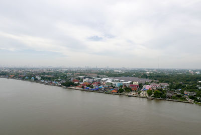 Scenic view of river by cityscape against sky