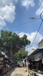 Street amidst trees and buildings against sky