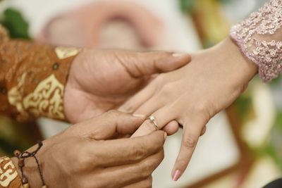 Cropped hand of man putting ring in woman finger