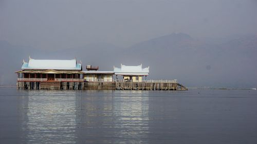 Stilt house on sea against sky