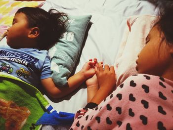 High angle view of siblings sleeping on bed at home