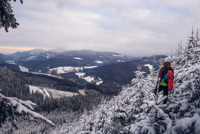 Candid portrait of man wearing winter clothes overlooking the snowy area of beskydy mountains.