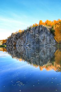 Reflection of trees in lake against blue sky