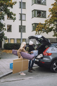 Mature couple loading luggage in car trunk during house relocation
