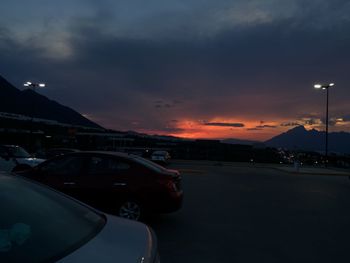 Cars on mountain against sky at sunset