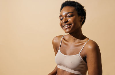 Portrait of young woman standing against pink background