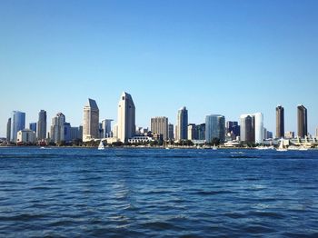 City at waterfront against blue sky