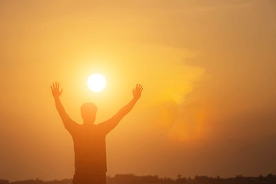 Silhouette person holding sun during sunset