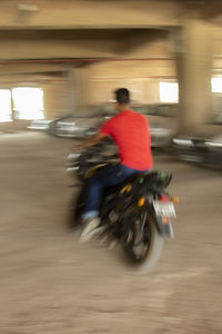 Blurred motion of man riding motorcycle on road in city
