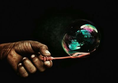 Cropped hand holding bubble on wand