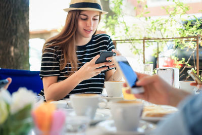 Young woman using smart phone in restaurant