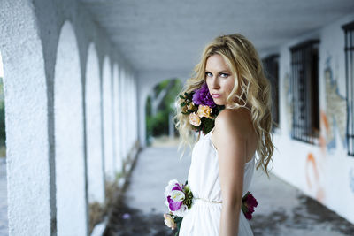 Portrait of young woman standing against white wall