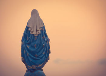 Rear view of woman standing against orange sky