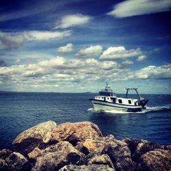 Boats in sea against cloudy sky