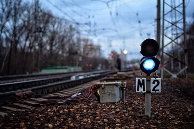 Railroad signal by tracks against sky