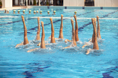 Low section of female swimmers synchronized swimming in pool