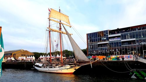 Sailboats in river against buildings in city