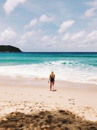 Rear view of woman on beach against sky