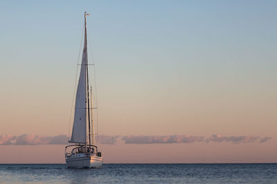 Sailboat on sea against sky during sunset