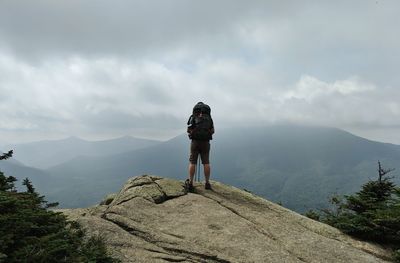 Rear view of man standing on mountain against sky