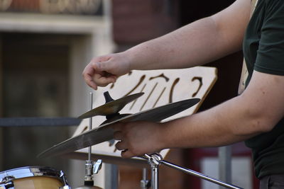 Midsection of man adjusting cymbal