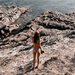 Rear view of woman on rock at beach