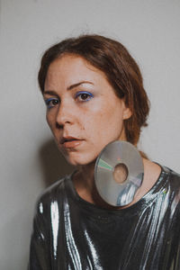 Portrait of young woman with compact disk against wall