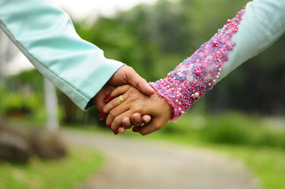 Cropped of groom holding hands of bride