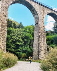 Arch bridge amidst trees against sky