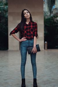 Full length portrait of beautiful young woman standing on footpath