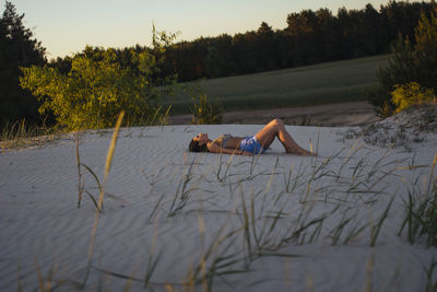 Woman lying on the sand at sunset time