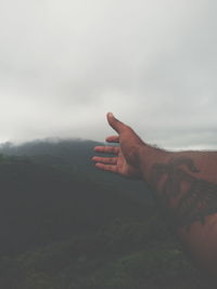 Midsection of person on mountain against sky