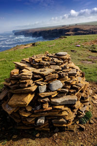 Stack of wood on field against sky