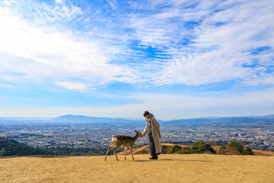 Rear view of woman walking on field against sky