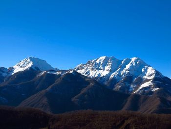 Scenic view of snowcapped mountains against clear blue sky