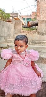 Portrait of a girl standing against pink wall