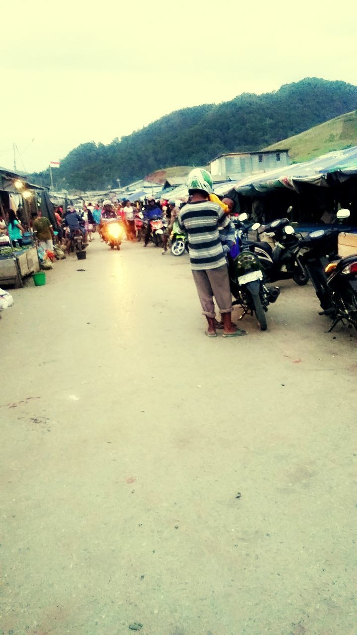 large group of people, transportation, men, clear sky, lifestyles, person, leisure activity, mountain, beach, mode of transport, sand, sky, medium group of people, incidental people, mixed age range, outdoors, group of people, vacations, copy space