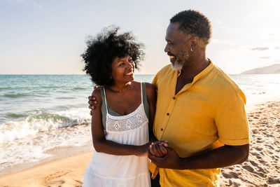 Side view of young friends standing at beach