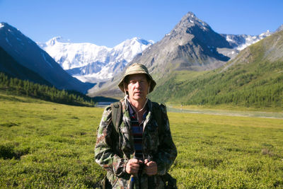 Portrait of man standing on field against mountains