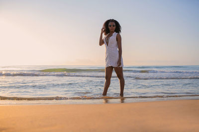 Full length of young woman standing at beach