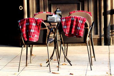 Empty chairs and tables against building